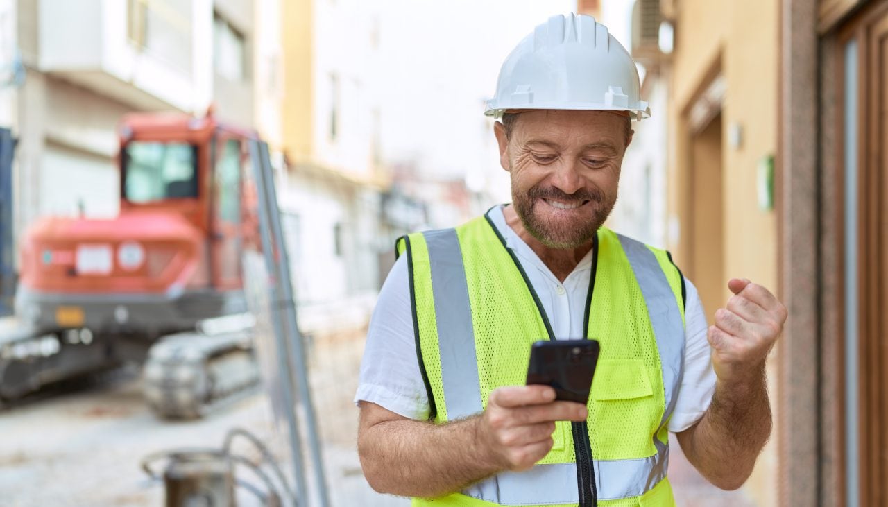 Middle age man architect using smartphone with winner expression at street